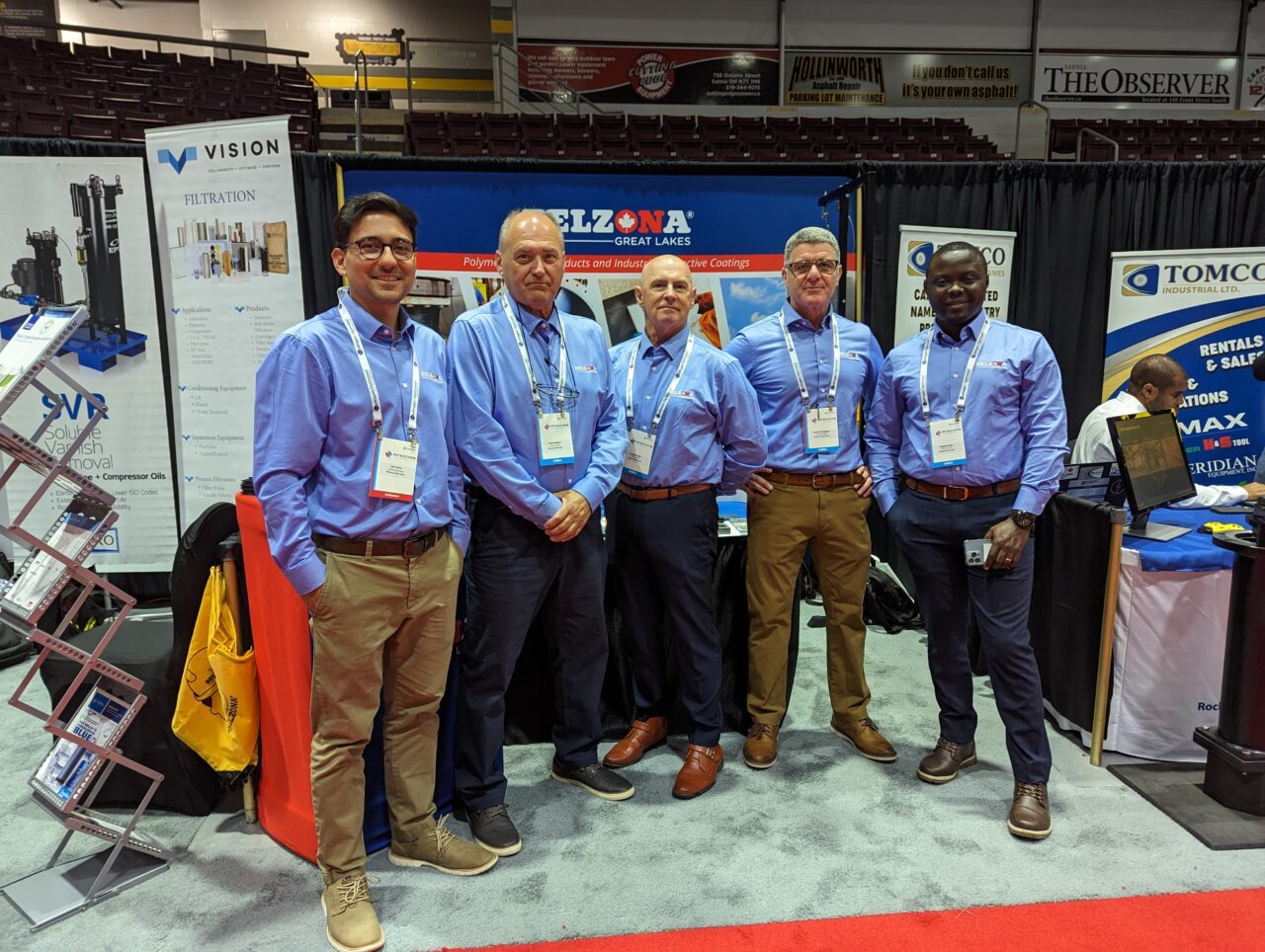 Five men posing for a picture at an exhibition.