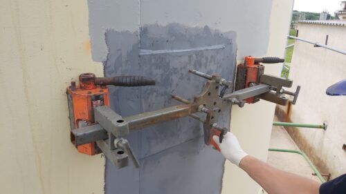 Magnets hold a plate attached to a tank wall
